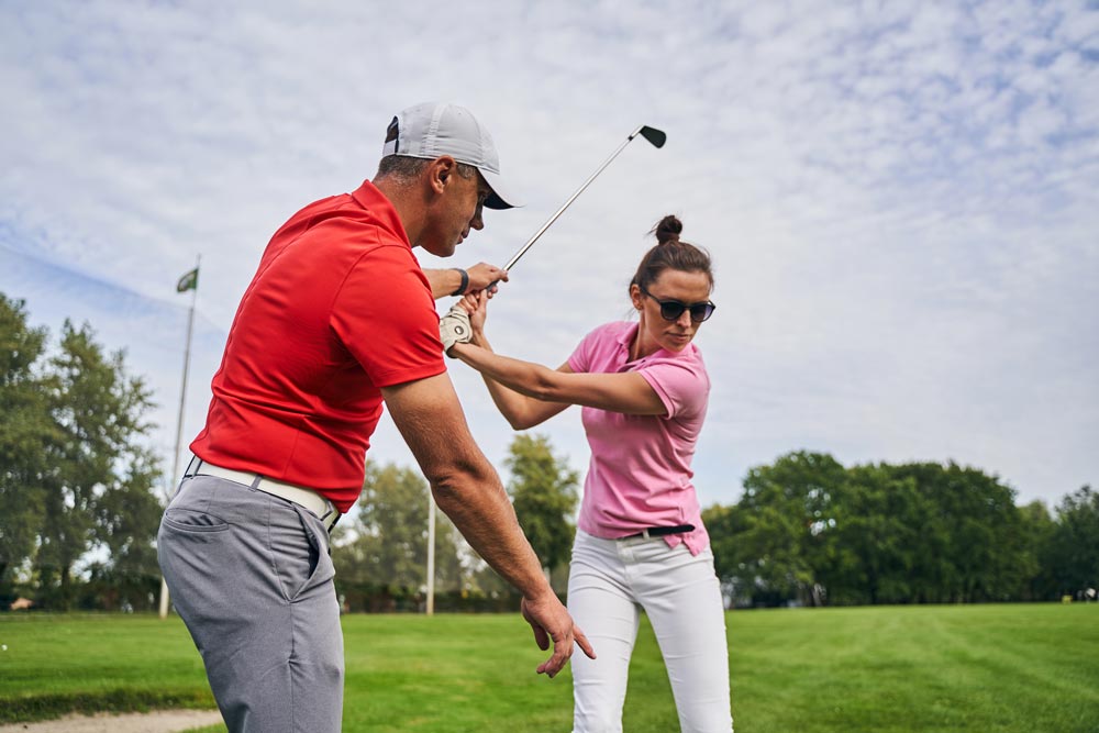 male instructor explaining the golf fundamentals to a female beginner