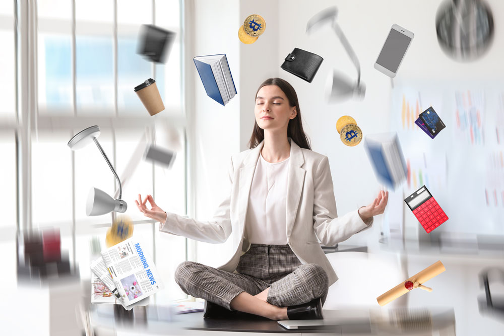 Different things flying around young businesswoman meditating in office